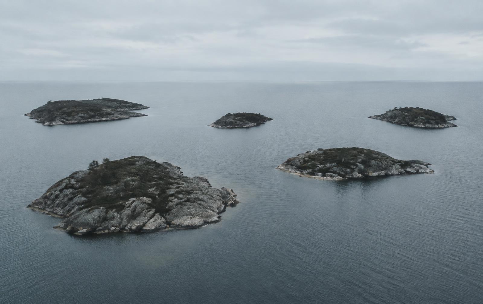 Five rocky islands in pale coastal water under overcast light