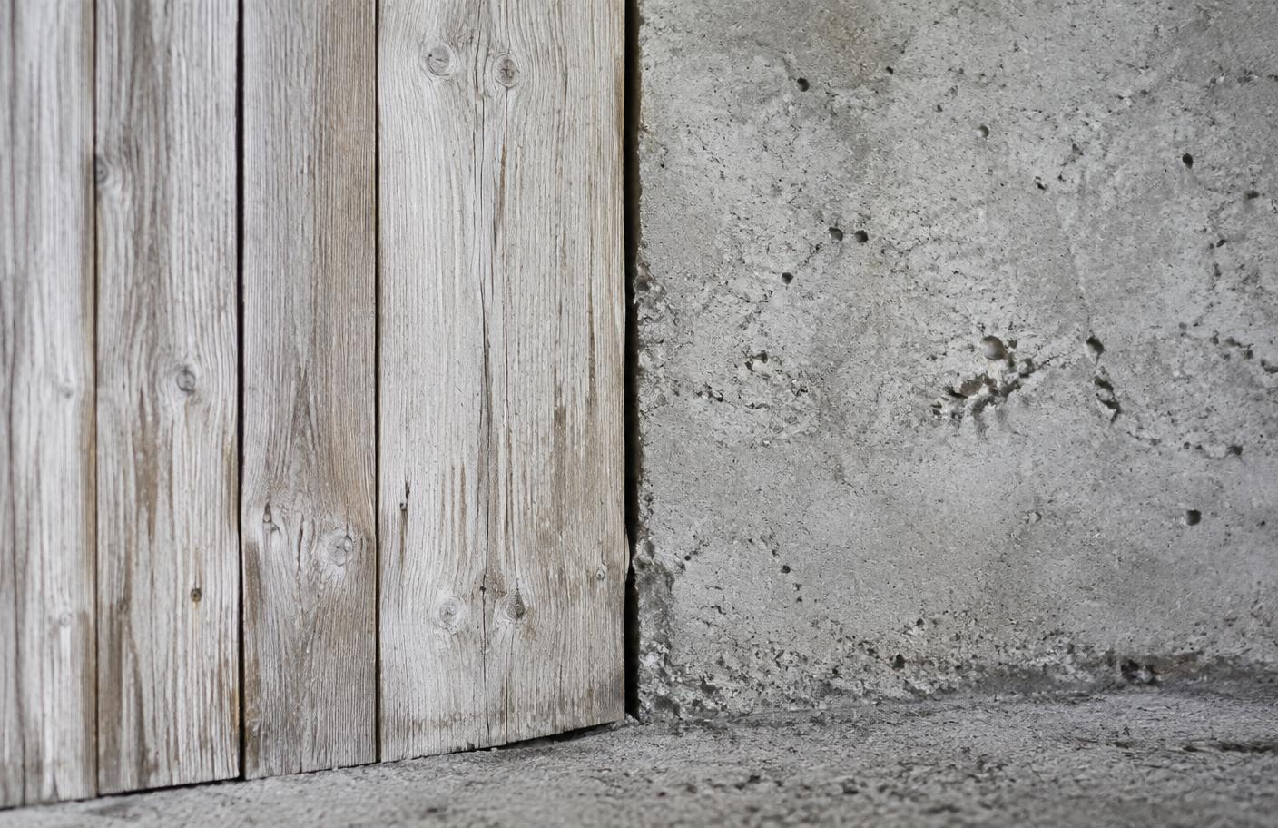 Weathered timber cladding meeting rough concrete